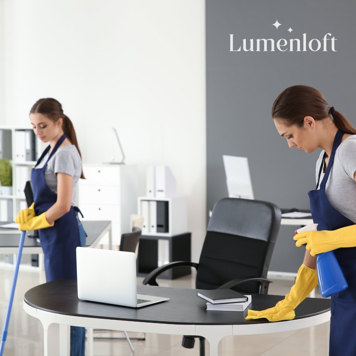 Two cleaning professionals in blue aprons and yellow gloves disinfecting an office desk and workspace at Lumenloft
